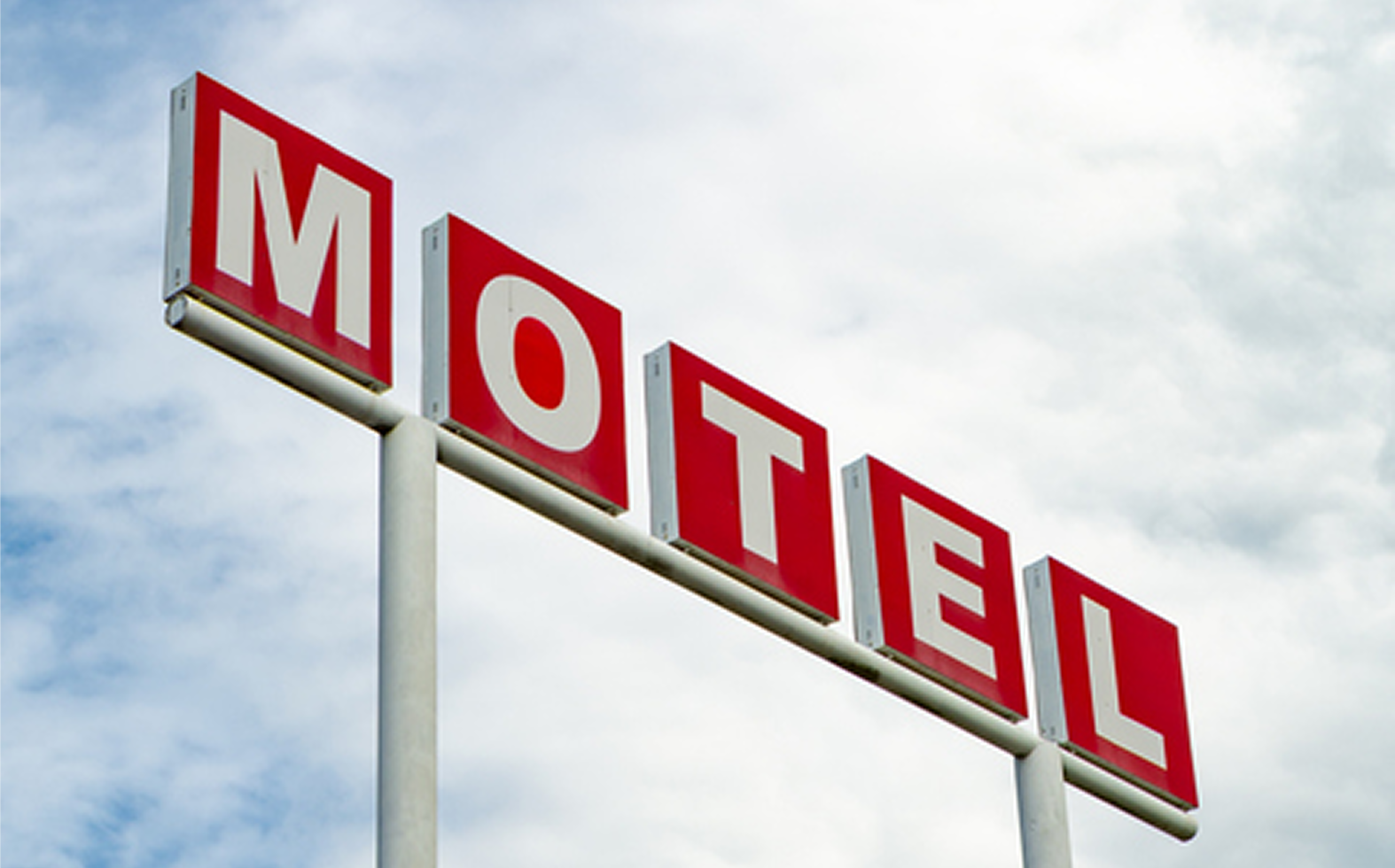 Motel sign against cloudy sky
