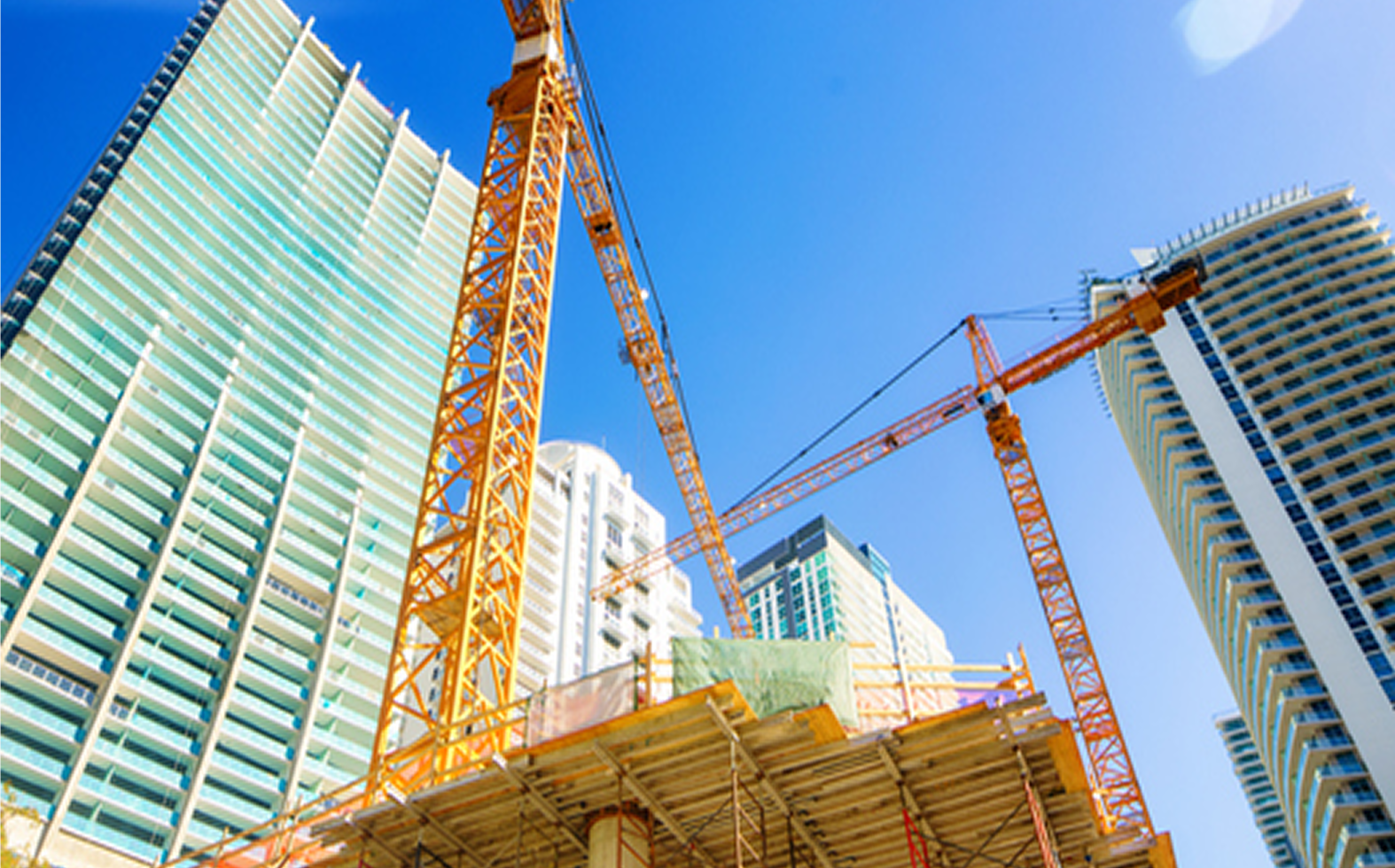 Construction cranes among tall skyscrapers